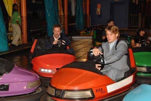 Dr. House and Dr. Chase in seperete red bumper cars whilst dressed up in suits in the middle of bumping into eachother.